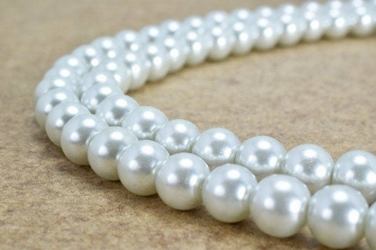 Double strand white pearl necklace on beige background.