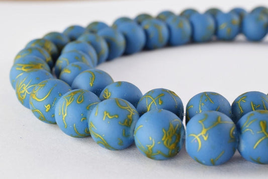 Blue and gold clay bead necklace on white background.