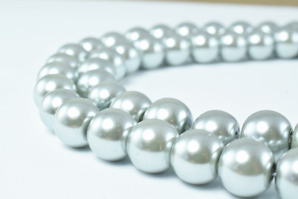 Silver pearl necklace on white background.