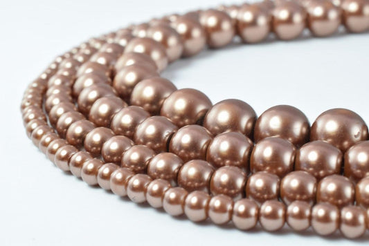 Brown pearl bead necklaces in varying sizes on white background.