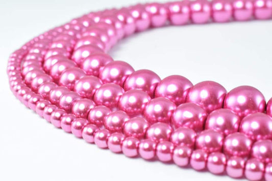 Pink pearl bead necklace strands on white background.