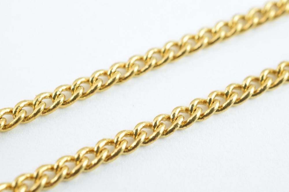 Gold curb chain necklace on white background.