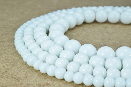 White beaded necklace on beige background.