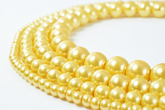 Golden pearl necklace strands on white background.