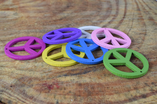 Colorful wooden peace sign pendants on wood surface.