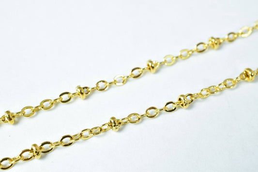 Gold cable chain necklace with ring beads on white background.