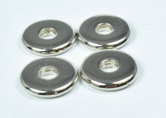 Four round silver metal washers on a white background.