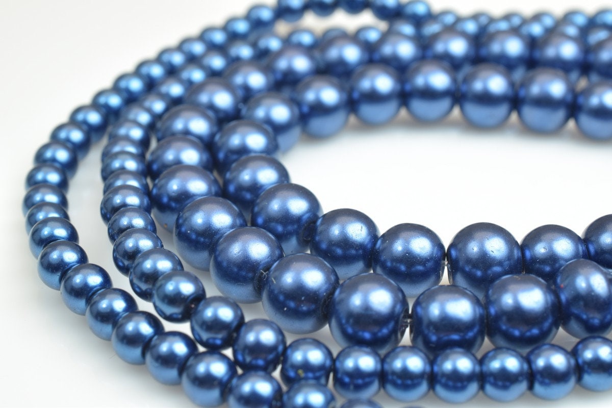 String of glossy blue pearls on a white surface.