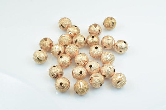 Gold textured round beads on white background.