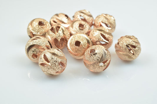 Rose gold textured spacer beads on white background.