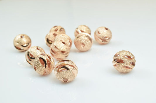 Rose gold textured spacer beads on white background.