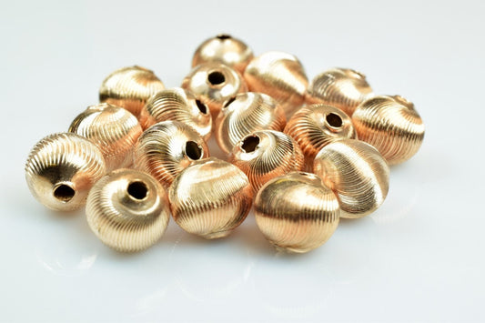 Gold ribbed spacer beads on white background.