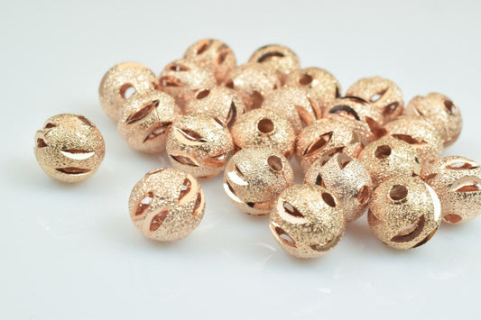 Rose gold textured round spacer beads on white background.