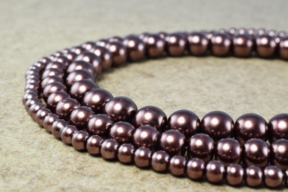 Shiny brown pearl bead strands on beige surface.