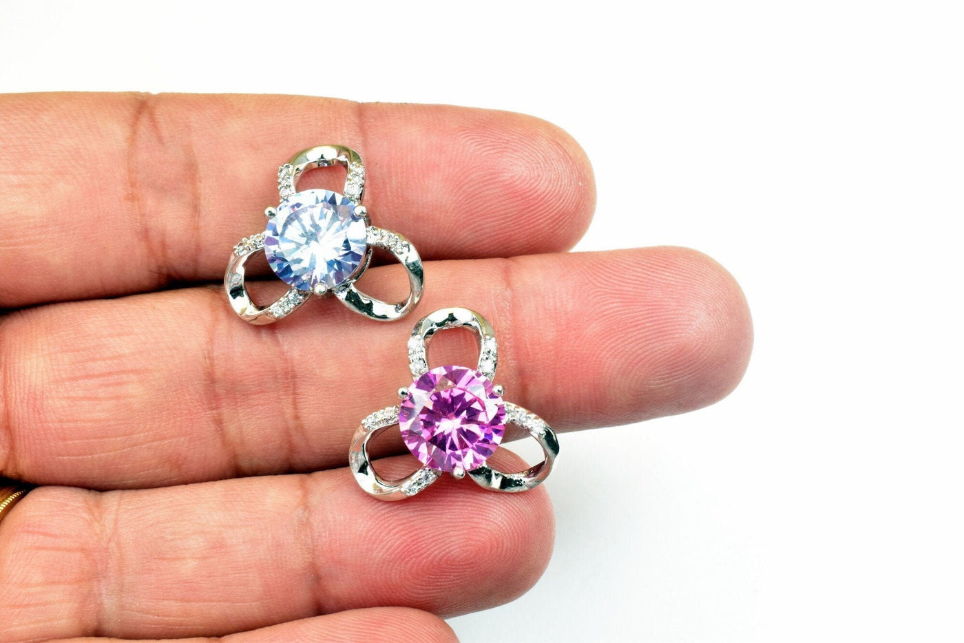 Silver and cubic zirconia earrings with blue and pink stones on hand.