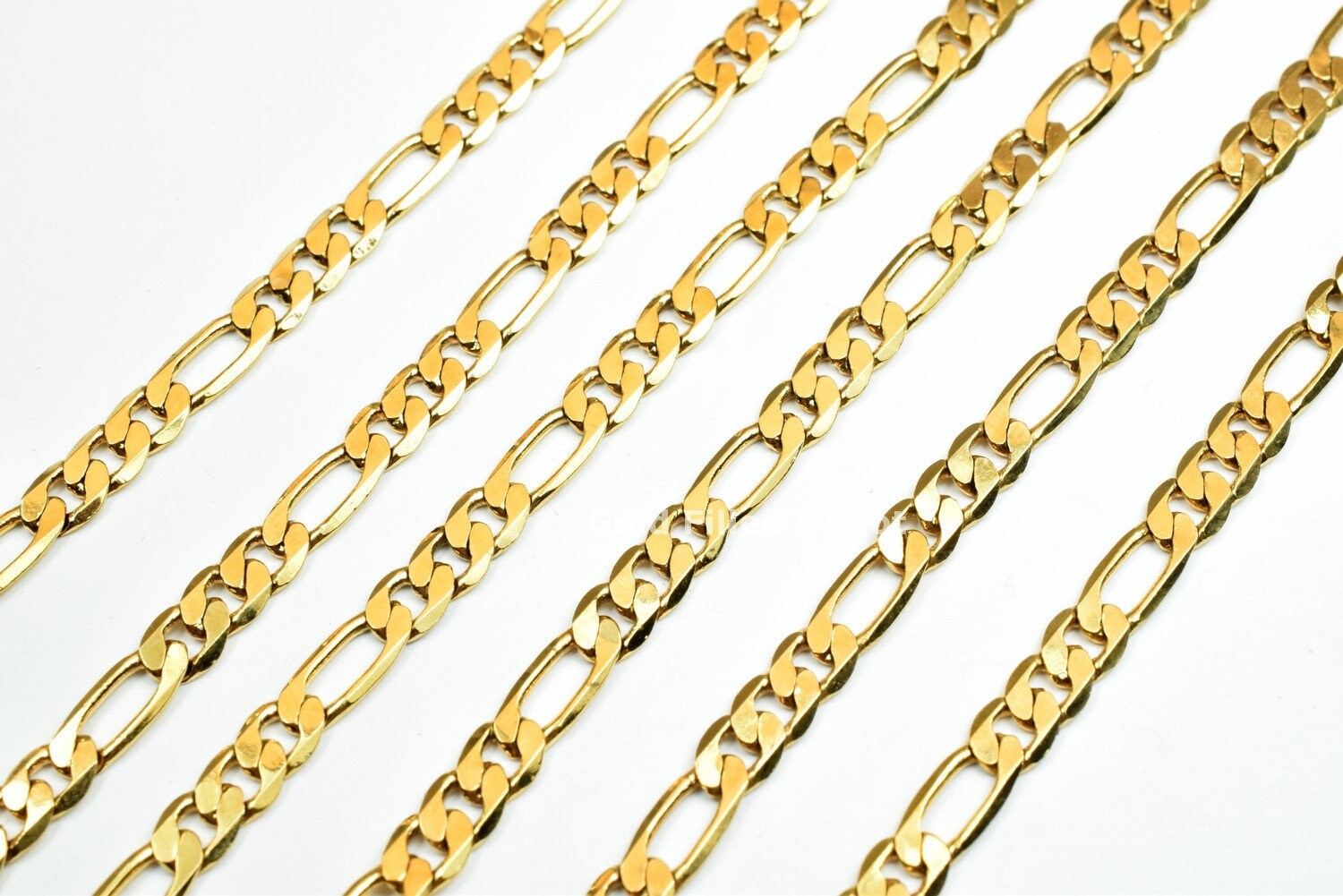 Gold Figaro chain pattern on white background.