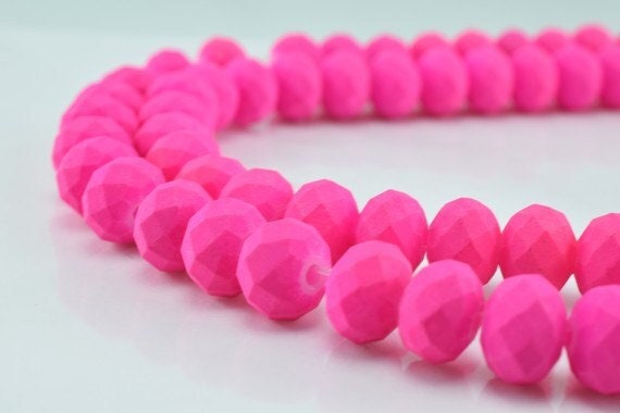 Bright pink faceted glass beads in a strand on white background.