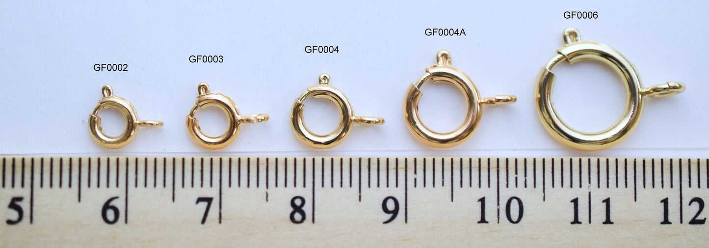 Gold-filled spring ring clasps of various sizes with ruler measurement.