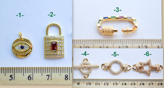 Assorted gold and gemstone jewelry charms and clasps with ruler for scale.