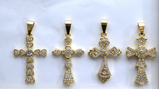 Gold diamond cross pendants on white background.