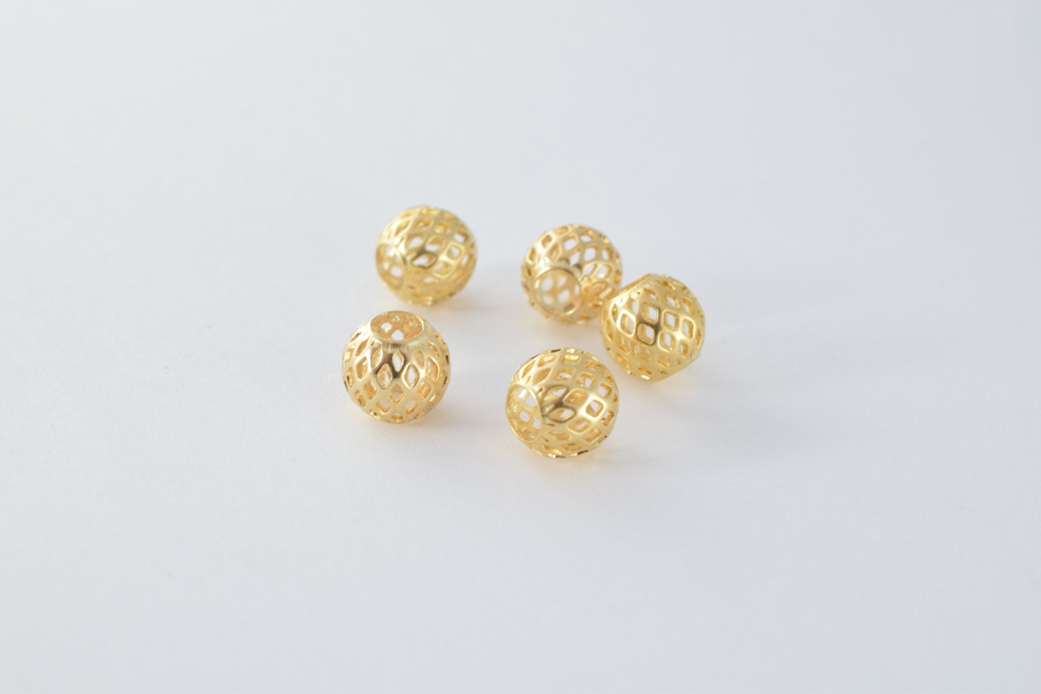 Gold filigree round beads on white background.